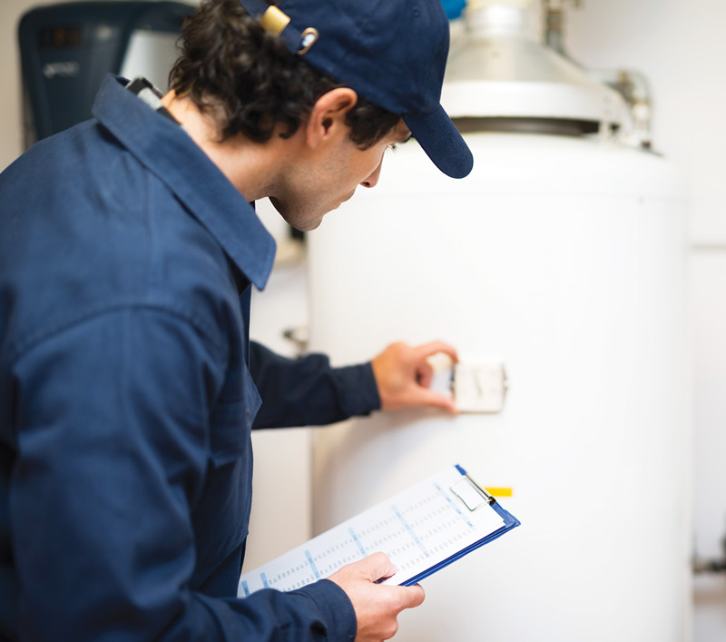 Man with clipboard checking a water heater