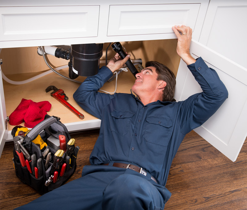 plumber at work under a sink